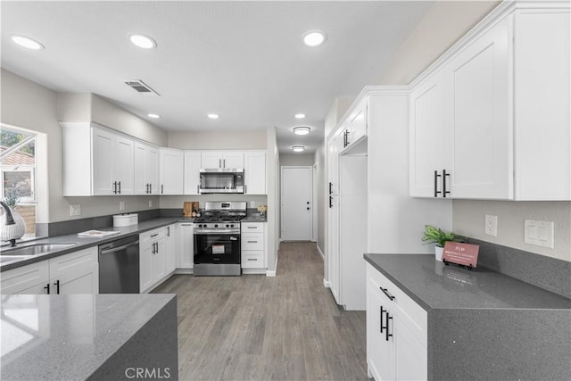 37921 Tackstem St, Palmdale, CA 93552 - kitchen featuring stainless steel appliances, white cabinetry, wood finished floors, dark stone countertops, and recessed lighting