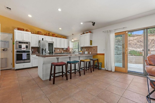 2605 Kauana Loa Dr, Escondido, CA 92029 - kitchen with appliances with stainless steel finishes, a peninsula, lofted ceiling, white cabinets, and light tile patterned flooring