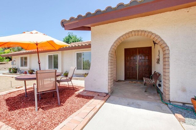2605 Kauana Loa Dr, Escondido, CA 92029 - view of exterior entry with stucco siding, a tile roof, and a patio