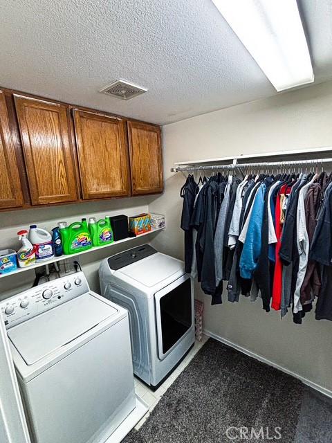 12920 La Costa Ct, Hesperia, CA 92344 - laundry room featuring washer and dryer, cabinet space, and a textured ceiling