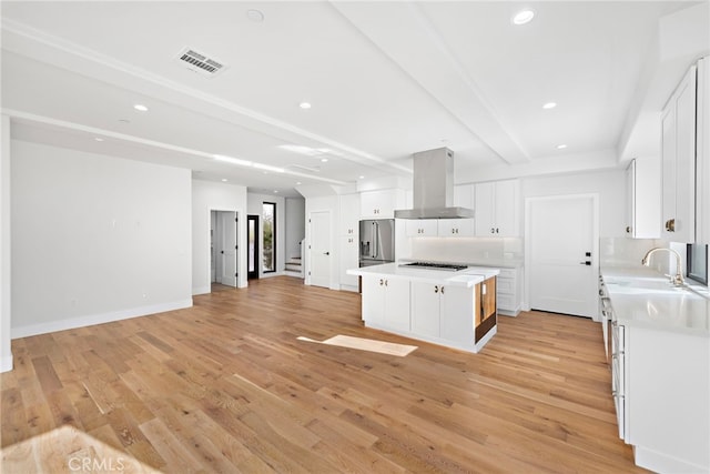 214 W Mariposa Unit B, San Clemente, CA 92672 - kitchen with wall chimney range hood, stainless steel refrigerator with ice dispenser, light countertops, open floor plan, and light wood-type flooring