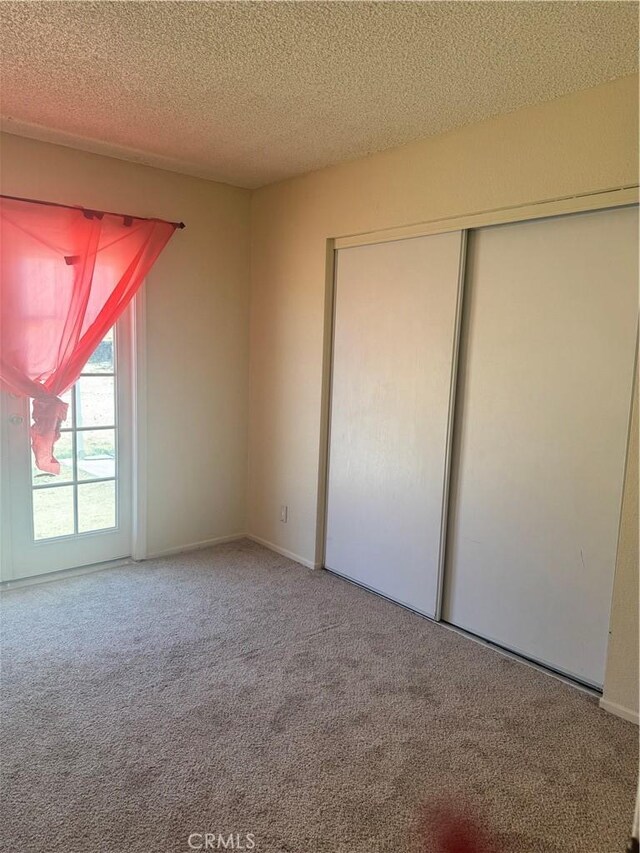 16840 Mackennas Gold Ave, Lake Los Angeles, CA 93591 - unfurnished bedroom featuring carpet floors, a textured ceiling, and a closet
