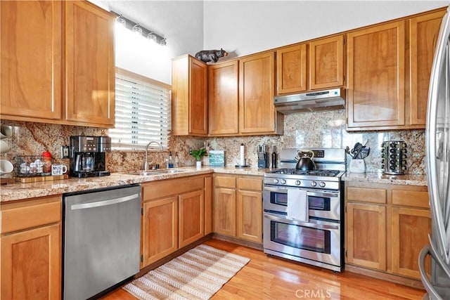 28410 Altamont Ct, Lake Arrowhead, CA 92352 - kitchen with appliances with stainless steel finishes, under cabinet range hood, backsplash, light wood finished floors, and light stone countertops