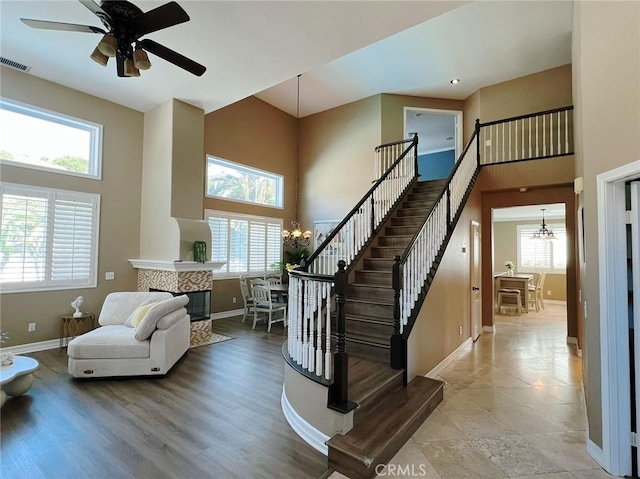 4717 Torrey Pines Dr, Chino Hills, CA 91709 - staircase with a chandelier, a towering ceiling, a tiled fireplace, and ceiling fan