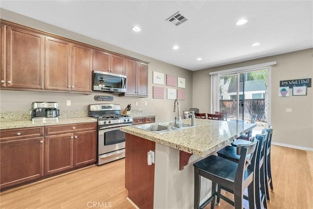 24934 Pine Creek Loop, Corona, CA 92883 - kitchen with appliances with stainless steel finishes, light wood-style flooring, a breakfast bar, recessed lighting, and light stone countertops