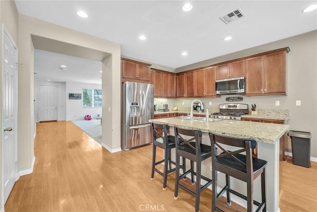 24934 Pine Creek Loop, Corona, CA 92883 - kitchen with appliances with stainless steel finishes, light wood-style flooring, a kitchen breakfast bar, recessed lighting, and an island with sink