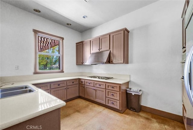 24934 Pine Creek Loop, Corona, CA 92883 - kitchen featuring under cabinet range hood, stainless steel gas cooktop, light colored carpet, light countertops, and brown cabinetry