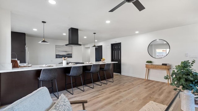 6117 Parkside Ave, San Diego, CA 92139 - kitchen featuring island exhaust hood, light countertops, a breakfast bar, light wood finished floors, and ceiling fan