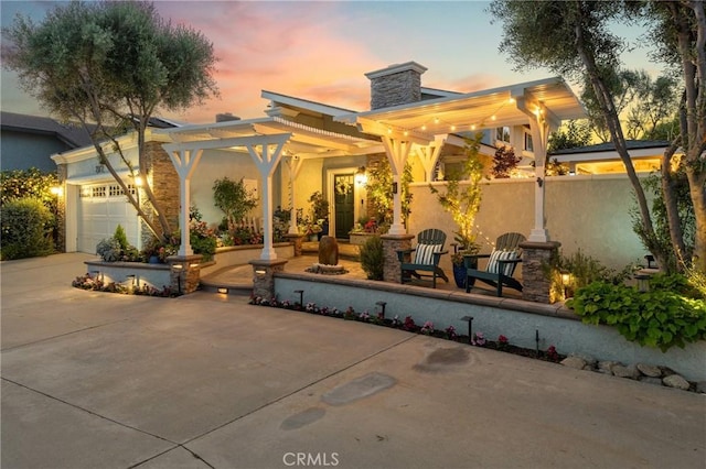 2172 N Pami Cir, Orange, CA 92867 - back of house at dusk with stucco siding, a chimney, a garage, a pergola, and concrete driveway
