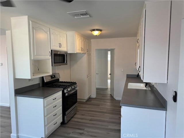 5781 Lime Ave, Cypress, CA 90630 - kitchen featuring appliances with stainless steel finishes, dark countertops, wood finished floors, and white cabinets