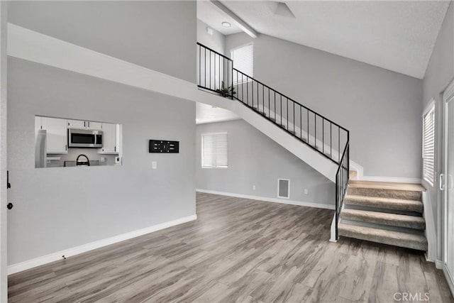 12178 Galaxy St, Victorville, CA 92392 - unfurnished living room with plenty of natural light, high vaulted ceiling, wood finished floors, and stairs