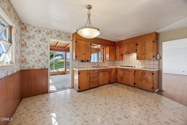3180 Grove St, Ventura, CA 93003 - kitchen featuring a wainscoted wall, brown cabinetry, backsplash, tile countertops, and hanging light fixtures