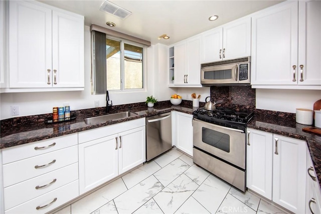 11949 Goshen Ave Unit 308, Los Angeles, CA 90049 - kitchen featuring appliances with stainless steel finishes, light marble finish flooring, white cabinets, dark stone countertops, and recessed lighting