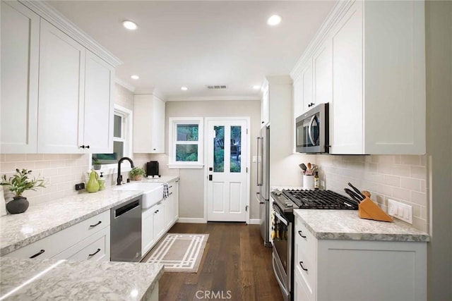 6541 Tokay Rd, Tujunga, CA 91042 - kitchen featuring appliances with stainless steel finishes, white cabinetry, dark wood-style flooring, crown molding, and backsplash
