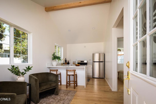 221 N 7th St, Santa Paula, CA 93060 - kitchen featuring freestanding refrigerator, a kitchen bar, a peninsula, light wood finished floors, and white cabinetry