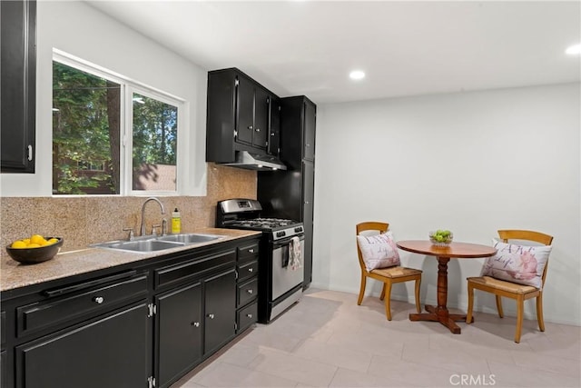 27917 Squirrel Ln, Lake Arrowhead, CA 92352 - kitchen with stainless steel gas stove, dark cabinetry, under cabinet range hood, backsplash, and recessed lighting