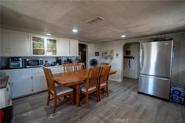 22731 Bryman Rd, Oro Grande, CA 92368 - dining area featuring arched walkways, light wood finished floors, a textured ceiling, recessed lighting, and washer / dryer