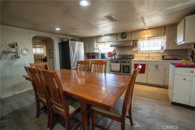 22731 Bryman Rd, Oro Grande, CA 92368 - dining room featuring arched walkways, healthy amount of natural light, light wood finished floors, recessed lighting, and a textured ceiling