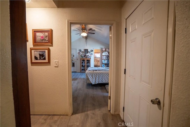 22731 Bryman Rd, Oro Grande, CA 92368 - corridor featuring wood finished floors, a textured wall, and vaulted ceiling
