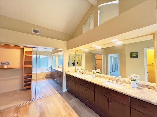 17346 Cold Spring Cir, Riverside, CA 92503 - bathroom featuring double vanity, a spacious closet, wood finished floors, and high vaulted ceiling