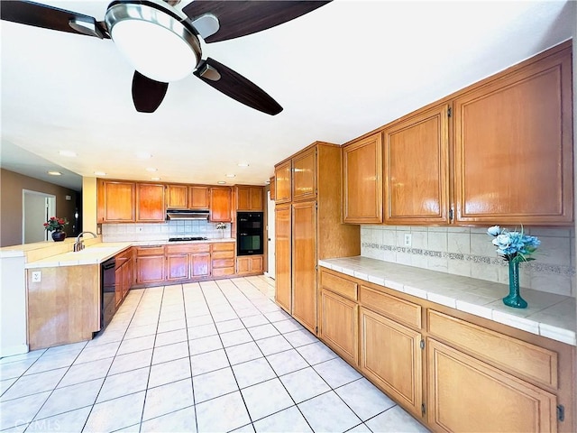 17346 Cold Spring Cir, Riverside, CA 92503 - kitchen featuring light tile patterned floors, under cabinet range hood, backsplash, a peninsula, and black appliances