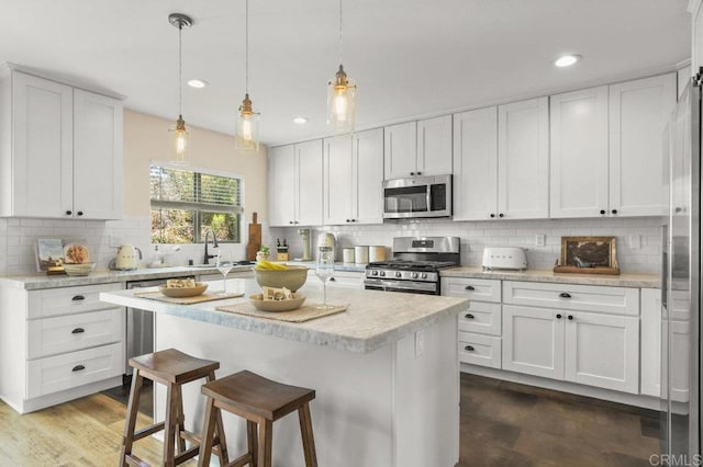 3585 Redwood St, San Diego, CA 92104 - kitchen featuring stainless steel appliances, backsplash, a breakfast bar area, light countertops, and white cabinetry