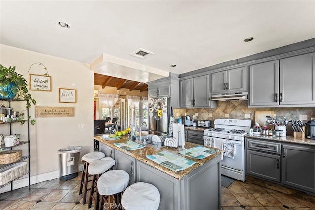 822 Corona Ave, Corona, CA 92879 - kitchen with white range with gas stovetop, under cabinet range hood, stainless steel refrigerator, gray cabinets, and recessed lighting