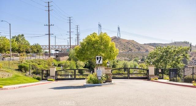 26370 Piazza Di Sarro, Newhall, CA 91321 - view of asphalt street featuring a gate, curbs, a gated entry, and street lighting