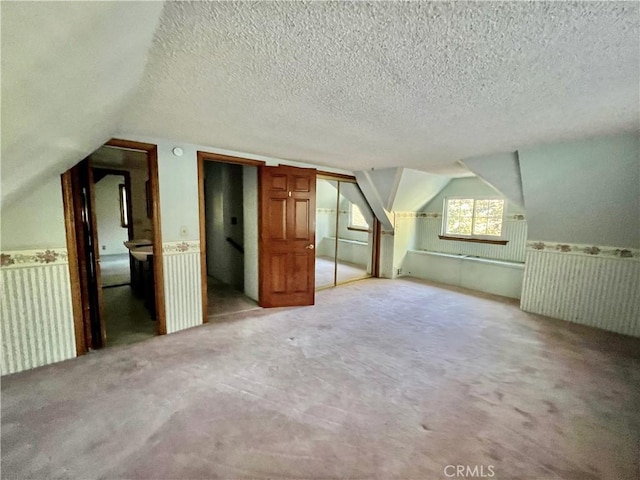 31016 Summit Dr, Running Springs, CA 92382 - additional living space featuring vaulted ceiling, light colored carpet, a wainscoted wall, and a textured ceiling