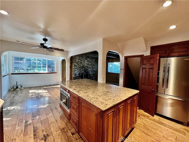 31016 Summit Dr, Running Springs, CA 92382 - kitchen featuring appliances with stainless steel finishes, arched walkways, light wood finished floors, light stone countertops, and recessed lighting