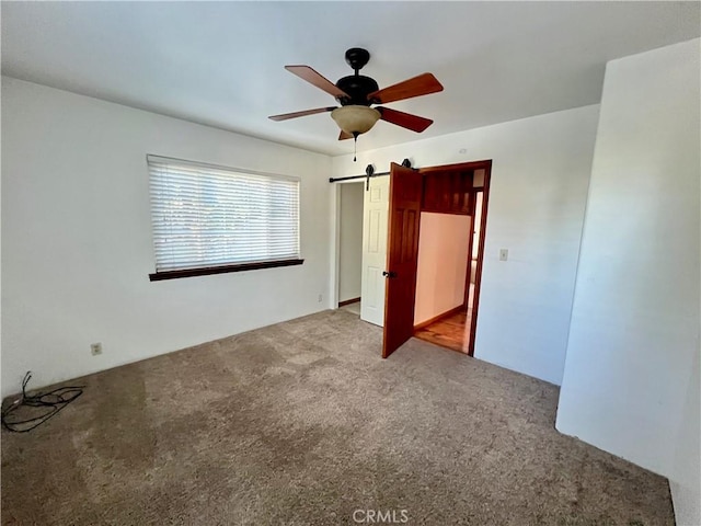 31016 Summit Dr, Running Springs, CA 92382 - unfurnished bedroom with carpet, a barn door, and a ceiling fan