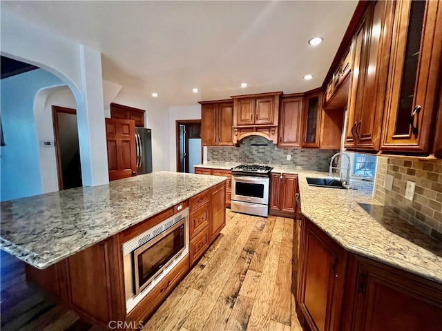 31016 Summit Dr, Running Springs, CA 92382 - kitchen featuring stainless steel appliances, light wood-type flooring, decorative backsplash, light stone counters, and a kitchen island