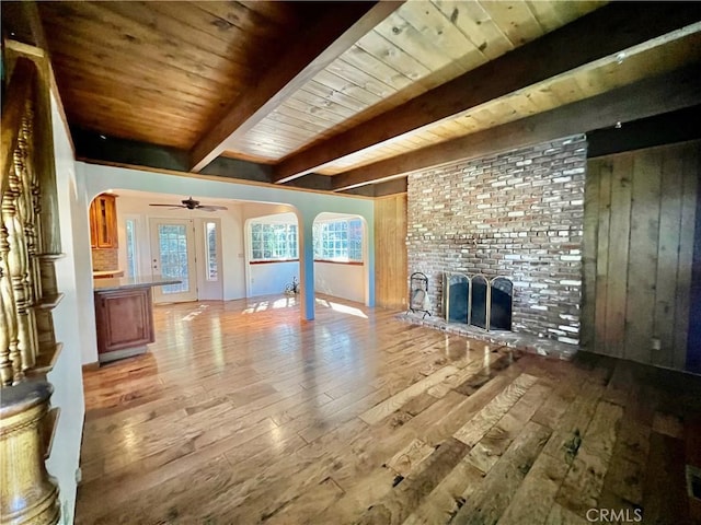 31016 Summit Dr, Running Springs, CA 92382 - unfurnished living room with arched walkways, light wood finished floors, a wooden ceiling with exposed beams, a fireplace, and ceiling fan