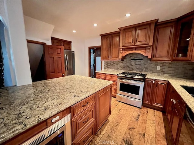 31016 Summit Dr, Running Springs, CA 92382 - kitchen featuring appliances with stainless steel finishes, light stone countertops, backsplash, light wood-style floors, and recessed lighting