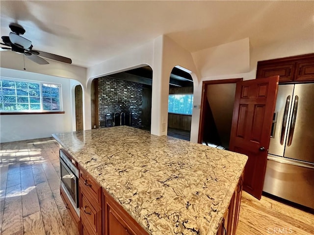 31016 Summit Dr, Running Springs, CA 92382 - kitchen featuring appliances with stainless steel finishes, arched walkways, ceiling fan, and light wood-style flooring