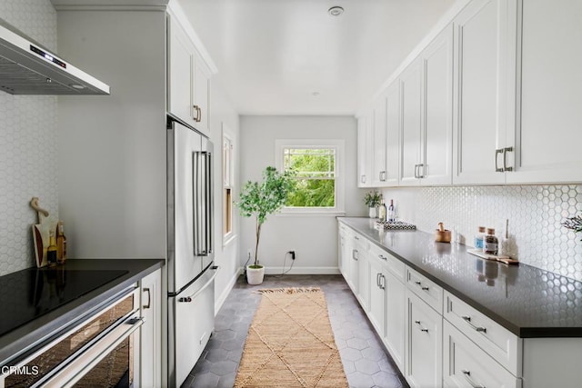 413 Sycamore Pl, Sierra Madre, CA 91024 - kitchen with wall chimney range hood, stainless steel appliances, dark countertops, decorative backsplash, and white cabinetry