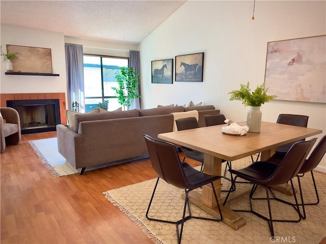 570 Peach St Unit 25, San Luis Obispo, CA 93401 - dining room featuring light wood finished floors, vaulted ceiling, a fireplace, and a textured ceiling