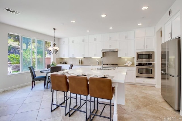 15240 Cayenne Creek Ct, San Diego, CA 92127 - kitchen with appliances with stainless steel finishes, light countertops, under cabinet range hood, a chandelier, and an island with sink