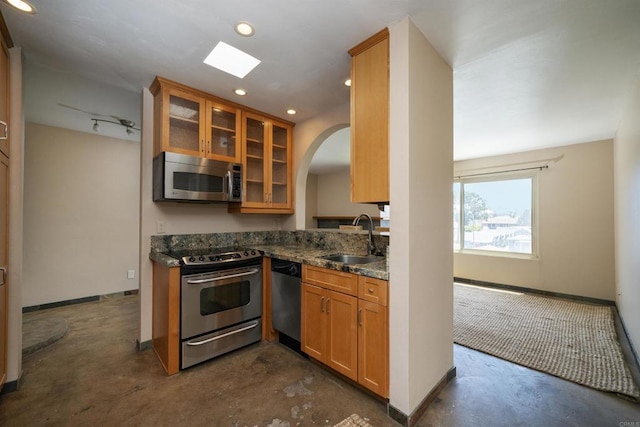 5155 W Point Loma Blvd Unit 9, San Diego, CA 92107 - kitchen featuring appliances with stainless steel finishes, concrete floors, glass insert cabinets, arched walkways, and brown cabinetry