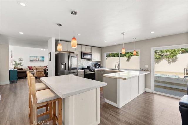 2040 Cape Cod Ct, Claremont, CA 91711 - kitchen featuring appliances with stainless steel finishes, a peninsula, light countertops, wood finished floors, and recessed lighting