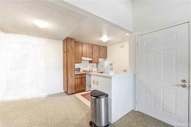4565 Alamo St Unit H, Simi Valley, CA 93063 - kitchen with white appliances, under cabinet range hood, light countertops, a peninsula, and brown cabinetry