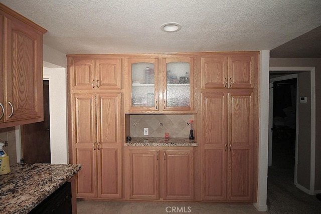 38103 Dividing Line St, Yermo, CA 92398 - kitchen featuring light stone counters, glass insert cabinets, decorative backsplash, a textured ceiling, and black dishwasher