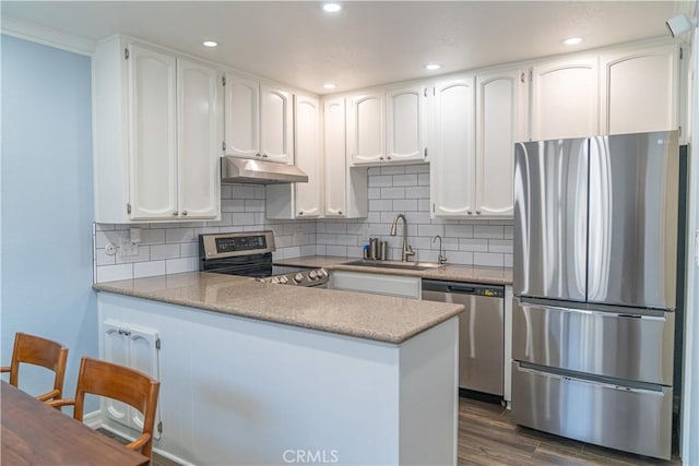 1845 Anaheim Ave Unit 27, Costa Mesa, CA 92627 - kitchen featuring appliances with stainless steel finishes, under cabinet range hood, a peninsula, white cabinetry, and dark wood-style floors