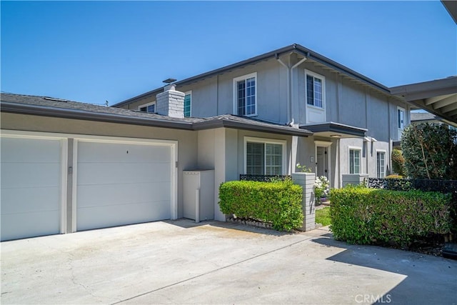 1845 Anaheim Ave Unit 27, Costa Mesa, CA 92627 - view of front of property featuring driveway, stucco siding, an attached garage, and a chimney