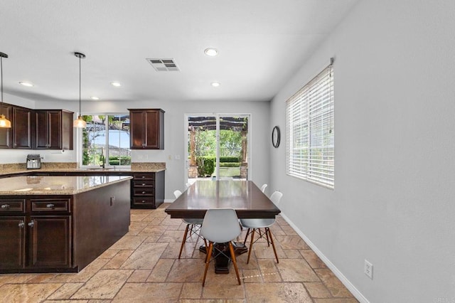 27792 Elderberry St, Murrieta, CA 92562 - kitchen with stone tile flooring, recessed lighting, dark brown cabinetry, pendant lighting, and light stone countertops