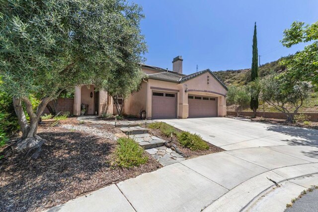 27792 Elderberry St, Murrieta, CA 92562 - view of front facade with an attached garage, concrete driveway, a chimney, and stucco siding
