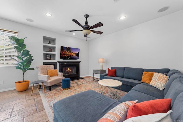 27792 Elderberry St, Murrieta, CA 92562 - living room with built in features, recessed lighting, a glass covered fireplace, a ceiling fan, and stone tile flooring