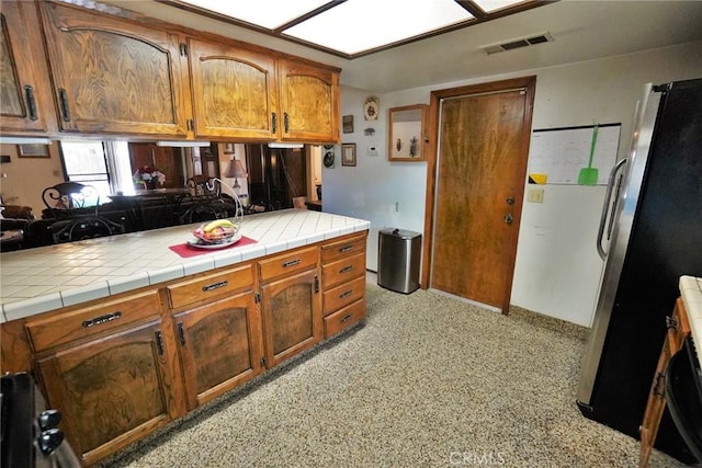 1200 Oxford Way, Hanford, CA 93230 - kitchen featuring brown cabinets, freestanding refrigerator, and tile counters