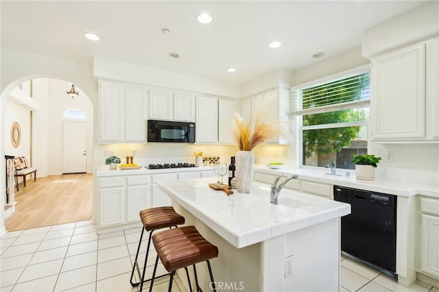 501 Newman Cir, Placentia, CA 92870 - kitchen featuring black appliances, an island with sink, white cabinets, arched walkways, and recessed lighting