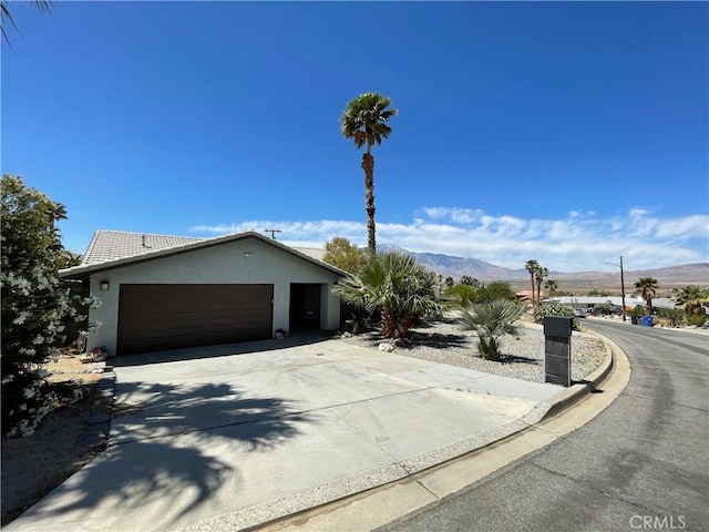 9830 Mesquite Ave, Desert Hot Springs, CA 92240 - ranch-style house with a mountain view, stucco siding, driveway, and a garage